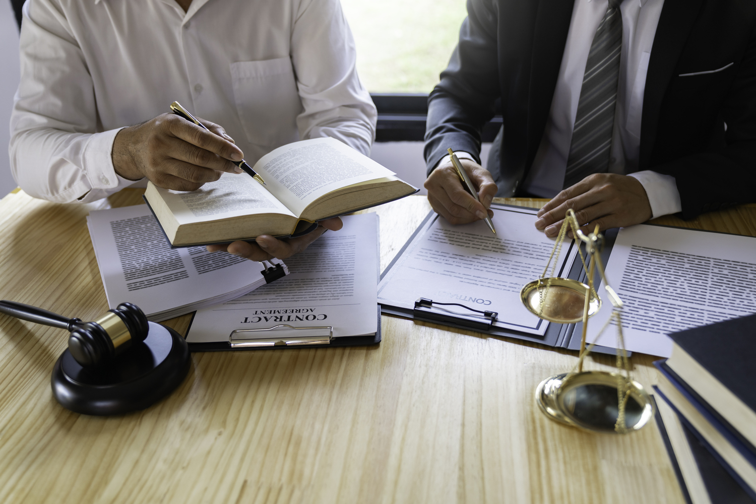 Abogado asesorando a un cliente en un despacho de abogados en Madrid, con estanterías llenas de libros jurídicos de fondo